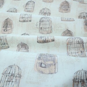 May include: A light blue fabric with a repeating pattern of brown birdcages. The birdcages are drawn in a vintage style with intricate details.