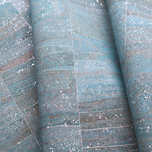 May include: A close-up of a blue and silver cork fabric with a grid pattern. The fabric has a speckled texture and a subtle shimmer.