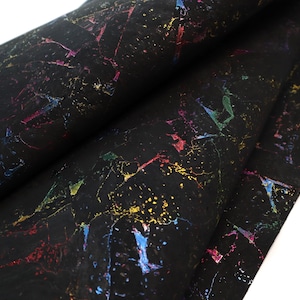 May include: A roll of black cork fabric with a textured surface. The fabric is decorated with colorful, irregular splashes of yellow, blue, red, and green, creating a vibrant, abstract pattern. The material is folded, revealing the underside.