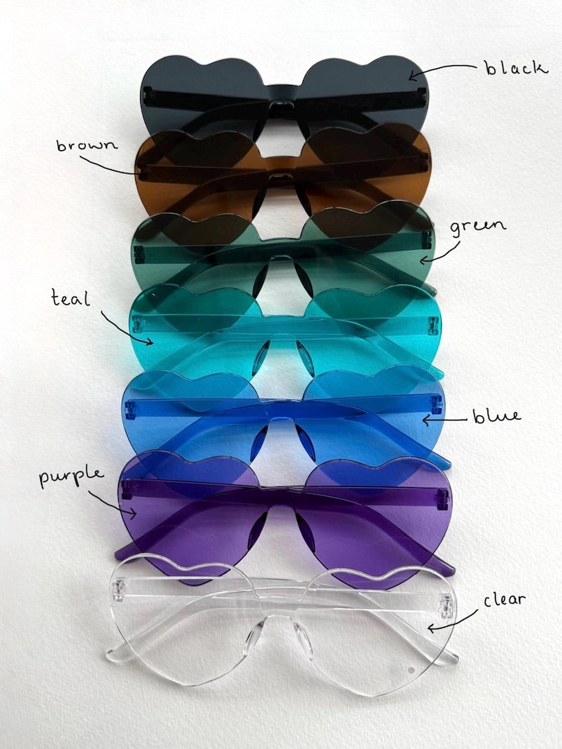 May include: A stack of heart-shaped sunglasses in various colors: black, brown, green, teal, blue, purple, and clear. The sunglasses have a rimless design and are arranged vertically, showcasing the different lens colors.