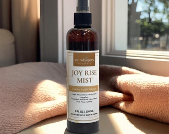 May include: A brown glass bottle of "JOY RISE MIST" with a black spray nozzle. The label reads "Golden Uplift Edition" and lists ingredients. The bottle contains 8 fl oz / 236 mL of product.