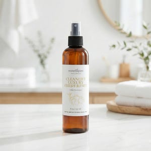 May include: A brown glass spray bottle of "CLEANLIFT LUXURY FRESH RESET" odor remover. The label includes the brand name "ecowhispers NATURALS" and the volume, 8 oz / 237 ml. The bottle has a black spray nozzle and is set against a bathroom background.