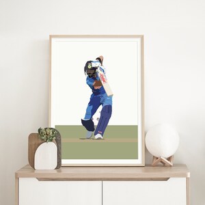 May include: A framed illustration of a cricket player in a blue uniform swinging a bat. The player is wearing a helmet and is in a batting stance. The background is a green field.