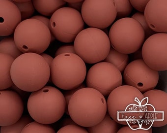 May include: A close-up of a pile of 20mm brown silicone beads. The beads are smooth and have a matte finish.