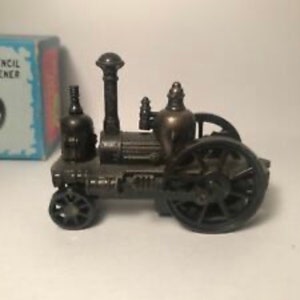 May include: A vintage-style metal pencil sharpener shaped like a steam engine. The sharpener is painted in a dark bronze color and has intricate details. The sharpener has a large wheel on the back and a smaller wheel on the front.