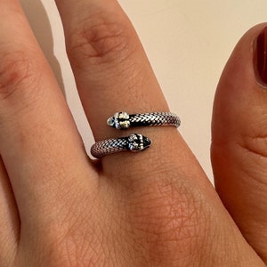 May include: A silver snake ring with a textured design. The ring is open and wraps around the finger.