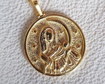 May include: Gold pendant necklace with a round medallion featuring a detailed image of a woman with a crescent moon and stars.