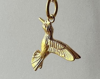May include: A gold hummingbird pendant necklace. The hummingbird is in flight with its wings spread out. The necklace is on a delicate gold chain.
