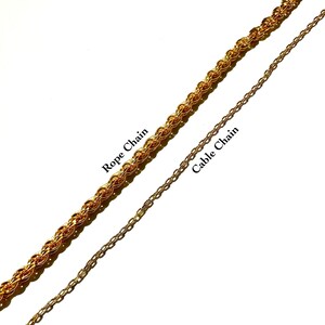 Op de afbeelding: Twee gouden kettingen, een met het label "Rope Chain" en de andere met het label "Cable Chain". De touwketting is dikker en heeft een ingewikkelder ontwerp dan de kabelketting.