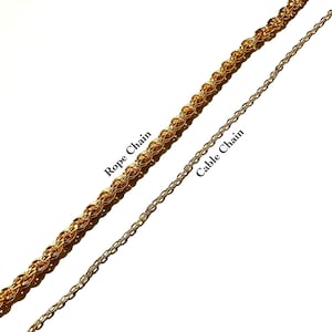 May include: Two gold-colored chains are displayed against a white background. One is a Rope Chain, and the other is a Cable Chain. The Rope Chain is thicker and more textured, while the Cable Chain is thinner and more delicate.
