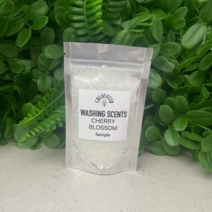 May include: A small clear plastic bag containing white crystals. The bag has a label that reads "WASHING SCENTS CHERRY BLOSSOM Sample".