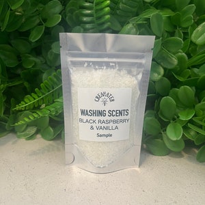 May include: A small white resealable bag containing a sample of white laundry detergent crystals. The bag has a label that reads "Washing Scents Black Raspberry & Vanilla Sample".