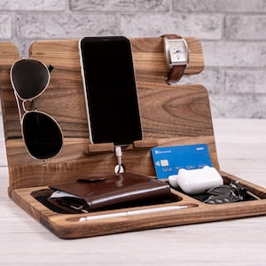 Può includere: Un organizzatore in legno con più scomparti per riporre gli oggetti di uso quotidiano. Presenta un supporto per telefono, un porta orologio, un porta occhiali da sole, uno slot per portafoglio, un gancio per chiavi e uno spazio per una carta di credito.