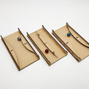 May include: Three wooden marble run tracks with a blue and green marble in the first track, a red marble in the second track, and a blue marble in the third track.