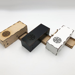 May include: Three wooden boxes with sliding drawers. The boxes are in natural wood, black, and white.