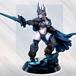 May include: A detailed figurine of a female warrior in a fantasy setting. She wears a dark blue cape, armour, and a horned helmet, holding a blue sword. The figure stands on a rocky base with a black circular stand. The colour palette includes blues, browns, and skin tones.