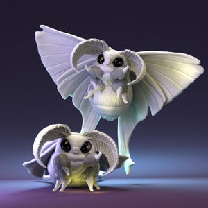 May include: Two off-white moth sculptures with large eyes and detailed wings. The moths are positioned in front of each other, creating a whimsical display. The sculptures have a soft, almost ethereal quality, with intricate body details.