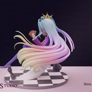 Pu&ograve; includere: Statuetta di un personaggio con lunghi capelli fluenti dai colori pastello, che indossa un abito viola e una corona. La figura tiene in mano delle carte da gioco ed &egrave; seduta su una piattaforma a scacchi. La base riporta il testo "Pink Studio" e il nome "Shiro".