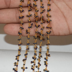 May include: Five strands of gold chain with iridescent black beads. The beads are small and clustered together, creating a delicate and elegant look.