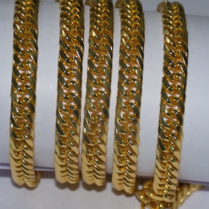Puede incluir: Cuatro pulseras de cadena doradas con un diseño trenzado.