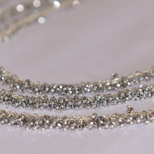 May include: A silver necklace made of small, round beads. The necklace is layered and has a delicate, feminine look.