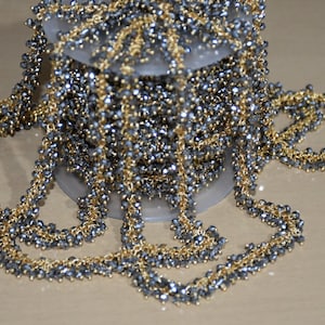 May include: A spool of gold and grey beaded chain trim. The chain is made of small, faceted beads and is perfect for adding a touch of sparkle to any project.