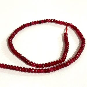 Puede incluir: Una hebra de cuentas de piedras preciosas facetadas de color rojo intenso. Las cuentas están enhebradas en un hilo rojo y tienen un diámetro aproximado de 4 mm.