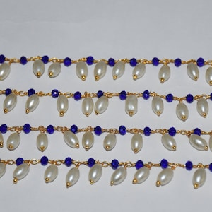 K&ouml;nnte beinhalten: Vier Str&auml;nge goldener Kette mit blauen Glasperlen und wei&szlig;en Perlentropfen, die an jedem Glied h&auml;ngen.