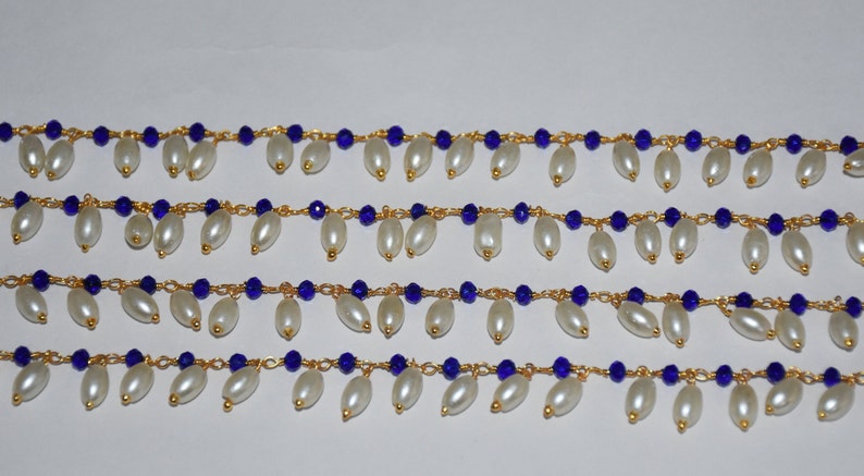 K&ouml;nnte beinhalten: Vier Str&auml;nge goldener Kette mit blauen Glasperlen und wei&szlig;en Perlentropfen, die an jedem Glied h&auml;ngen.