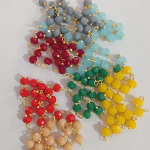 May include: Assortment of colorful glass beads with gold wire loops. The beads are in shades of red, blue, green, yellow, and beige.