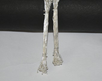 May include: Two bundles of silver floral wire with small silver beads at the ends. The wire is bundled together and tied with a silver wire.