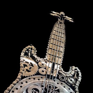 May include: A metal sculpture of an electric guitar made from recycled parts, including gears, chains, and a piston. The guitar is painted in a silver and black color scheme. The sculpture is signed "A Angelov The Metal Art Zone".