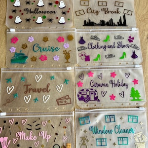 May include: Eight translucent plastic zipper pouches with punched holes for binders. Each pouch features unique vinyl decals including text like Halloween, City Break, Cruise, Clothing and Shoes, Travel, Caravan Holiday, Make Up, and Window Cleaner.