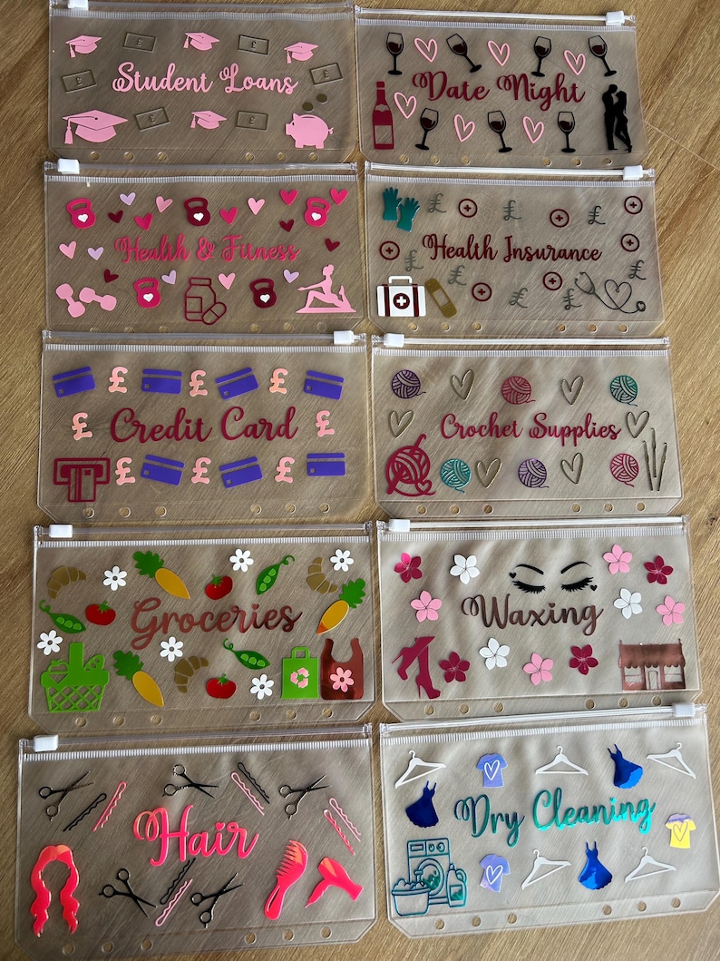 May include: Ten translucent plastic zipper pouches for binders, each featuring unique vinyl decals and text labels including Student Loans, Date Night, Health & Fitness, Health Insurance, Credit Card, Crochet Supplies, Groceries, Waxing, Hair, and Dry Cleaning.
