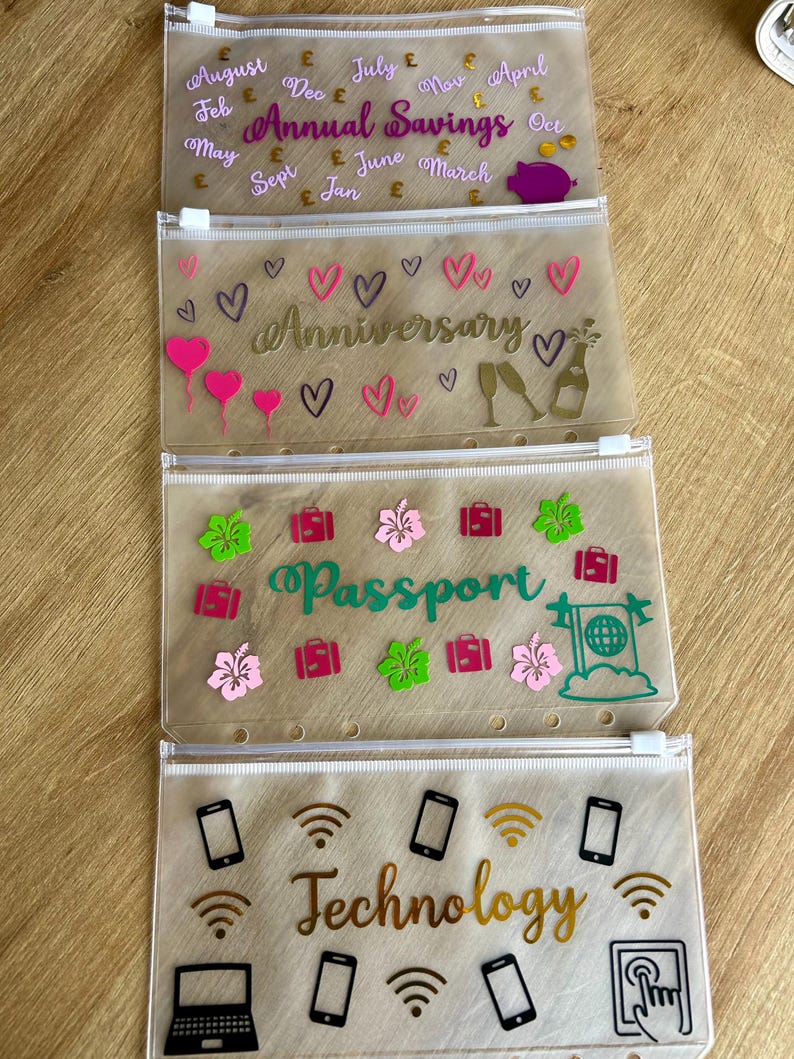 May include: Four translucent plastic zipper pouches with white zippers and punched holes for binders. The top pouch features the text Annual Savings with months and pound symbols. The second shows Anniversary with hearts and champagne. The third says Passport with suitcases and flowers. The bottom displays Technology with icons of phones, laptops, and Wi-Fi symbols.