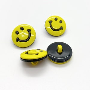 May include: Four yellow smiley face buttons with black outlines. One button has a black back with a hole for sewing.