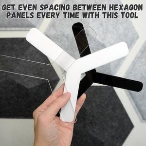 Puede incluir: Una herramienta de plástico blanco con forma curva, diseñada para ayudar a crear un espacio uniforme entre paneles hexagonales. La herramienta se sostiene en una mano, con el texto "GET EVEN SPACING BETWEEN HEXAGON PANELS EVERY TIME WITH THIS TOOL" visible en el fondo.