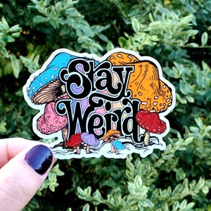 May include: A sticker with a colorful mushroom design and the text "Stay Weird".