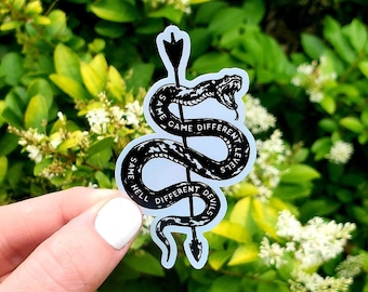 May include: Black and white sticker of a snake wrapped around an arrow with the text "Same Hell Different Devils" and "Same Game Different Level" on the snake.