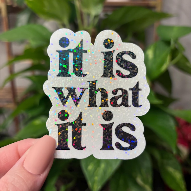 May include: A white sticker with a holographic finish features the text "it is what it is" in black lettering.