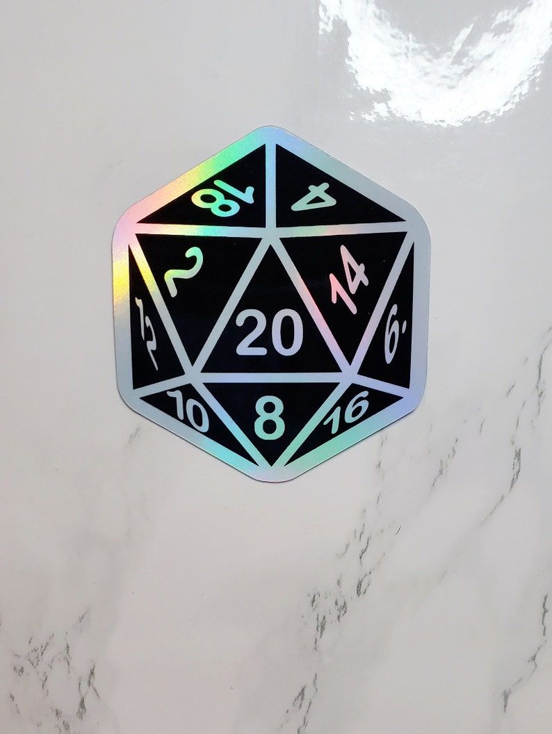 May include: A black and holographic sticker of a twenty-sided die, with white numbers. The die is a dodecahedron shape, with each face displaying a number from 2 to 20. The holographic effect creates a rainbow sheen.