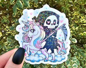 May include: A sticker featuring a cartoon Grim Reaper riding a unicorn. The Grim Reaper is wearing a black cloak with glitter and holding a scythe. The unicorn is pink and blue with a rainbow mane and tail. The sticker has a white background with pink hearts.