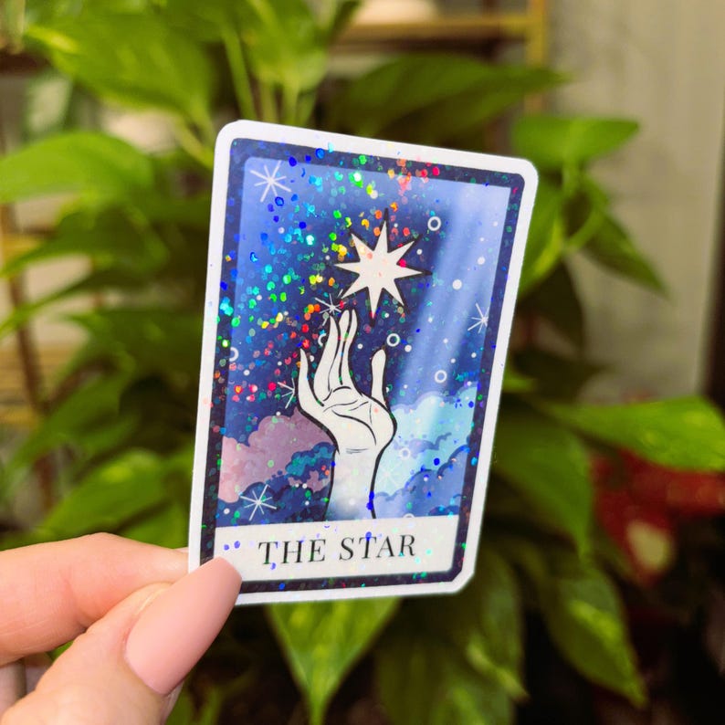May include: A tarot card with a blue, purple and white background. A hand reaches up to touch a white star. The card reads "THE STAR".