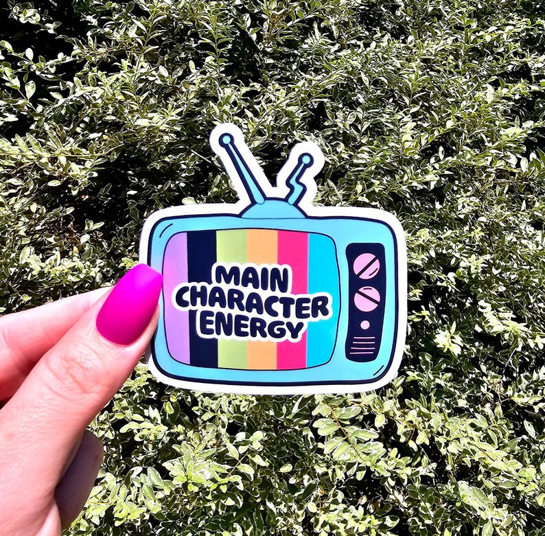 May include: A blue and white sticker of a retro television with a rainbow screen that says "Main Character Energy".