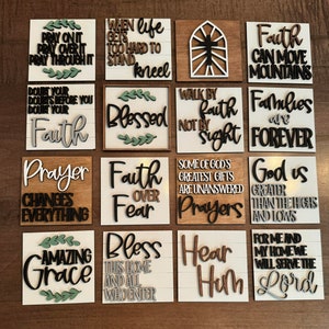 May include: Twelve wooden signs with inspirational quotes and sayings. The signs are painted in various colors, including white, black, brown, and green. The signs feature a variety of fonts and styles, and some have decorative elements such as leaves and crosses.