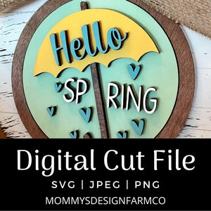 Puede incluir: Un archivo de corte digital para un proyecto de artesanía con temática primaveral. El diseño presenta un paraguas amarillo con la palabra "Hello" en él, y las palabras "Spring" debajo. El fondo es azul claro con corazones blancos.