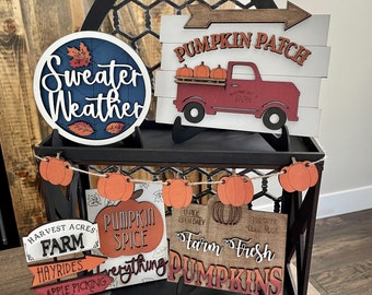 Könnte beinhalten: Ein Holzschild mit dem Text "Pumpkin Patch" und einem roten Lastwagen mit Kürbissen auf der Ladefläche. Es gibt weitere Schilder mit Herbstmotiven, darunter "Farm Fresh Pumpkins", "Pumpkin Spice" und "Harvest Acres Farm".