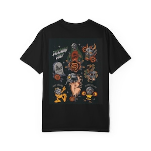 May include: Black t-shirt with a vibrant graphic design. The design incorporates illustrations of masked characters, roses, and the text "DOOMS DAY" and "ALL CAPS!". The tee has a standard crew neck and short sleeves.