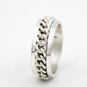 May include: A silver ring featuring a spinning chain design. The chain is made of small, linked circles.