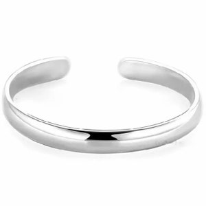 Può includere: Un semplice anello per dita dei piedi in argento con una superficie liscia e arrotondata.